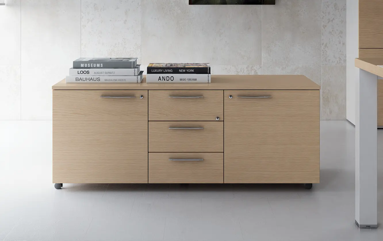 DEKKO Interiors | Αισθητική & Εργονομία στα Έπιπλα Γραφείου Asset – γραφείο με μεταλλική κατασκευή Η χαρακτηριστική σχεδίαση του γραφείου Asset Executive Office με μεταλλική κατασκευή ενισχύει την απλότητα των τετράγωνων σχημάτων και των ευθειών γραμμών. Ένα γραφείο που παραμένει τονισμένο με την πάροδο του χρόνου χάρη στα αυστηρά σχήματα και τον δυνατό σχεδιασμό του. Η σημαντική επιφάνεια εργασίας μελαμίνης, με πάχος 38 mm, στηρίζεται από τετράγωνα ατσάλινα πόδια, L. 80 mm, που υπογραμμίζουν τη στιβαρότητα και τη στιβαρότητα της κατασκευής. Τα πόδια ενώνονται, δύο προς δύο, με μια ορθογώνια εγκάρσια ράβδο (Π. 80 mm Υ. 30 mm) και είναι εξοπλισμένα με ένα ατσάλινο ένθετο εφοδιασμένο με πόδι ισοπέδωσης. Δύο δοκοί κάτω από το δάπεδο, συγκολλημένες στις εγκάρσιες δοκούς του σκέλους, ολοκληρώνουν τη δομή, σταθεροποιώντας την επιφάνεια εργασίας. Ιδιαίτερη προσοχή έχει δοθεί στις λεπτομέρειες: ένα μεταλλικό περίβλημα σε σχήμα χάλυβα (πάχους 1,2 mm), έχει σχεδιαστεί για να κρύβει την εγκάρσια δοκό του ποδιού, ενώ ένα πλαίσιο αλουμινίου ακολουθεί το προφίλ τόσο της δομής όσο και της κορυφής, δίνοντας κομψότητα στο σύνολο. τραπέζι.