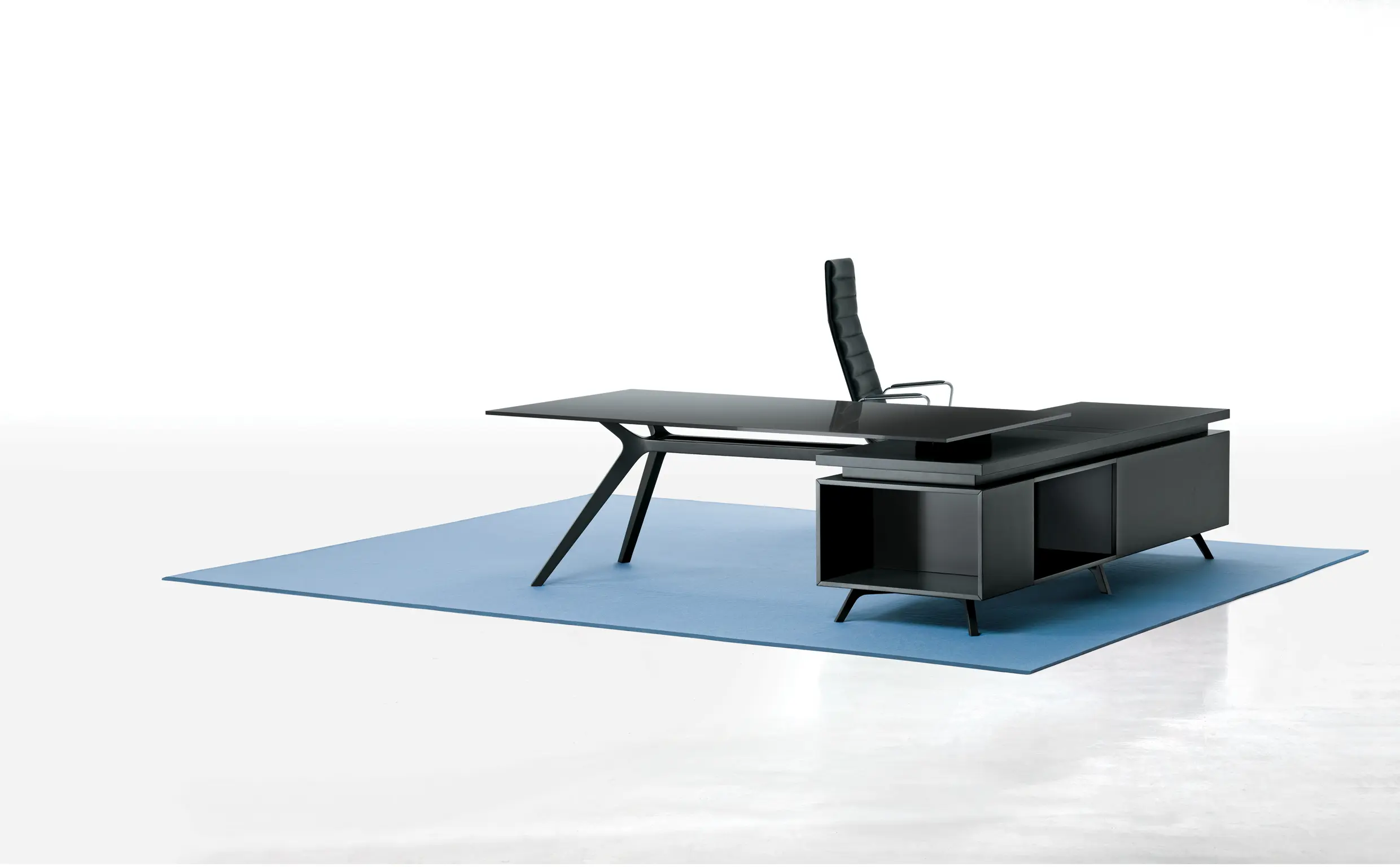 DEKKO Interiors | Αισθητική & Εργονομία στα Έπιπλα Γραφείου Η κατασκευή του γραφείου αποπνέει μια ευάερη και δυναμική αίσθηση, χάρη στην ξύλινη δομή του, η οποία είναι εμπνευσμένη από το στυλ "Mollinian". Αυτή η μοναδική κατασκευή στηρίζει είτε μια γυάλινη είτε μια ξύλινη επιφάνεια σε μια εντυπωσιακή ισορροπία αντίθετων δυνάμεων, δημιουργώντας ένα εντυπωσιακό οπτικό αποτέλεσμα. Το πολύτιμο ξύλο καρυδιάς παίζει κεντρικό ρόλο στον σχεδιασμό του γραφείου. Η επιφάνεια εργασίας, κατασκευασμένη από φυσικό καρυδιά ξύλο, είναι το αποκορύφωμα της υλικότητας και της χειροτεχνίας, με ένα συμπαγές προφίλ και στρογγυλεμένες άκρες που αναδεικνύουν τη φυσική ομορφιά του υλικού. Η γοητεία του κρυστάλλου συναντά την ισχυρή και στιβαρή αίσθηση του μαόνι kotibé στη δομή του γραφείου. Προτείνεται σε δύο εκδόσεις: λευκή και ανθρακί λάκα, προσφέροντας έτσι ευελιξία στον σχεδιασμό του εσωτερικού χώρου. Οι κρυστάλλινες επιφάνειες είναι διαθέσιμες σε τρεις εκδόσεις: εξαιρετικά διαφανές γυαλί, λευκό λακαρισμένο γυαλί, και καπνιστό γυαλί, όλα πάχους 15 mm, προσδίδοντας μία επιπλέον διάσταση πολυτέλειας.