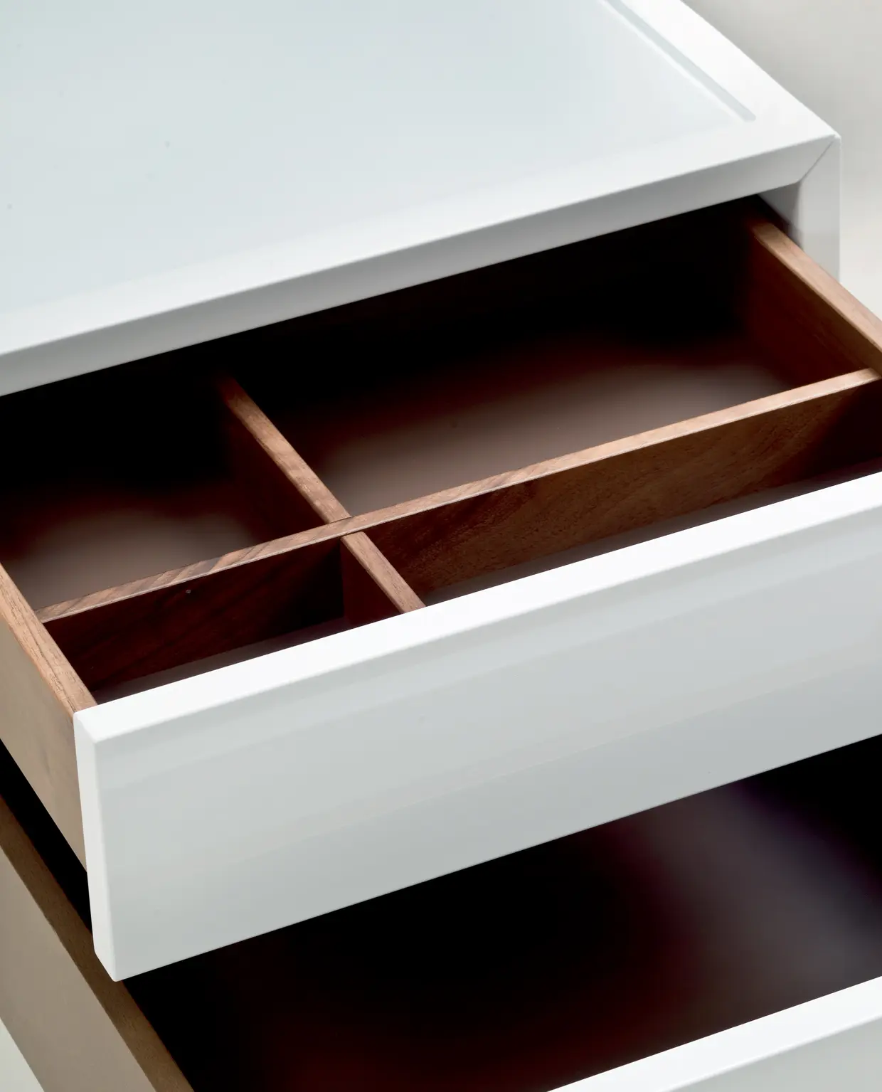 DEKKO Interiors | Αισθητική & Εργονομία στα Έπιπλα Γραφείου Η κατασκευή του γραφείου αποπνέει μια ευάερη και δυναμική αίσθηση, χάρη στην ξύλινη δομή του, η οποία είναι εμπνευσμένη από το στυλ "Mollinian". Αυτή η μοναδική κατασκευή στηρίζει είτε μια γυάλινη είτε μια ξύλινη επιφάνεια σε μια εντυπωσιακή ισορροπία αντίθετων δυνάμεων, δημιουργώντας ένα εντυπωσιακό οπτικό αποτέλεσμα. Το πολύτιμο ξύλο καρυδιάς παίζει κεντρικό ρόλο στον σχεδιασμό του γραφείου. Η επιφάνεια εργασίας, κατασκευασμένη από φυσικό καρυδιά ξύλο, είναι το αποκορύφωμα της υλικότητας και της χειροτεχνίας, με ένα συμπαγές προφίλ και στρογγυλεμένες άκρες που αναδεικνύουν τη φυσική ομορφιά του υλικού. Η γοητεία του κρυστάλλου συναντά την ισχυρή και στιβαρή αίσθηση του μαόνι kotibé στη δομή του γραφείου. Προτείνεται σε δύο εκδόσεις: λευκή και ανθρακί λάκα, προσφέροντας έτσι ευελιξία στον σχεδιασμό του εσωτερικού χώρου. Οι κρυστάλλινες επιφάνειες είναι διαθέσιμες σε τρεις εκδόσεις: εξαιρετικά διαφανές γυαλί, λευκό λακαρισμένο γυαλί, και καπνιστό γυαλί, όλα πάχους 15 mm, προσδίδοντας μία επιπλέον διάσταση πολυτέλειας.