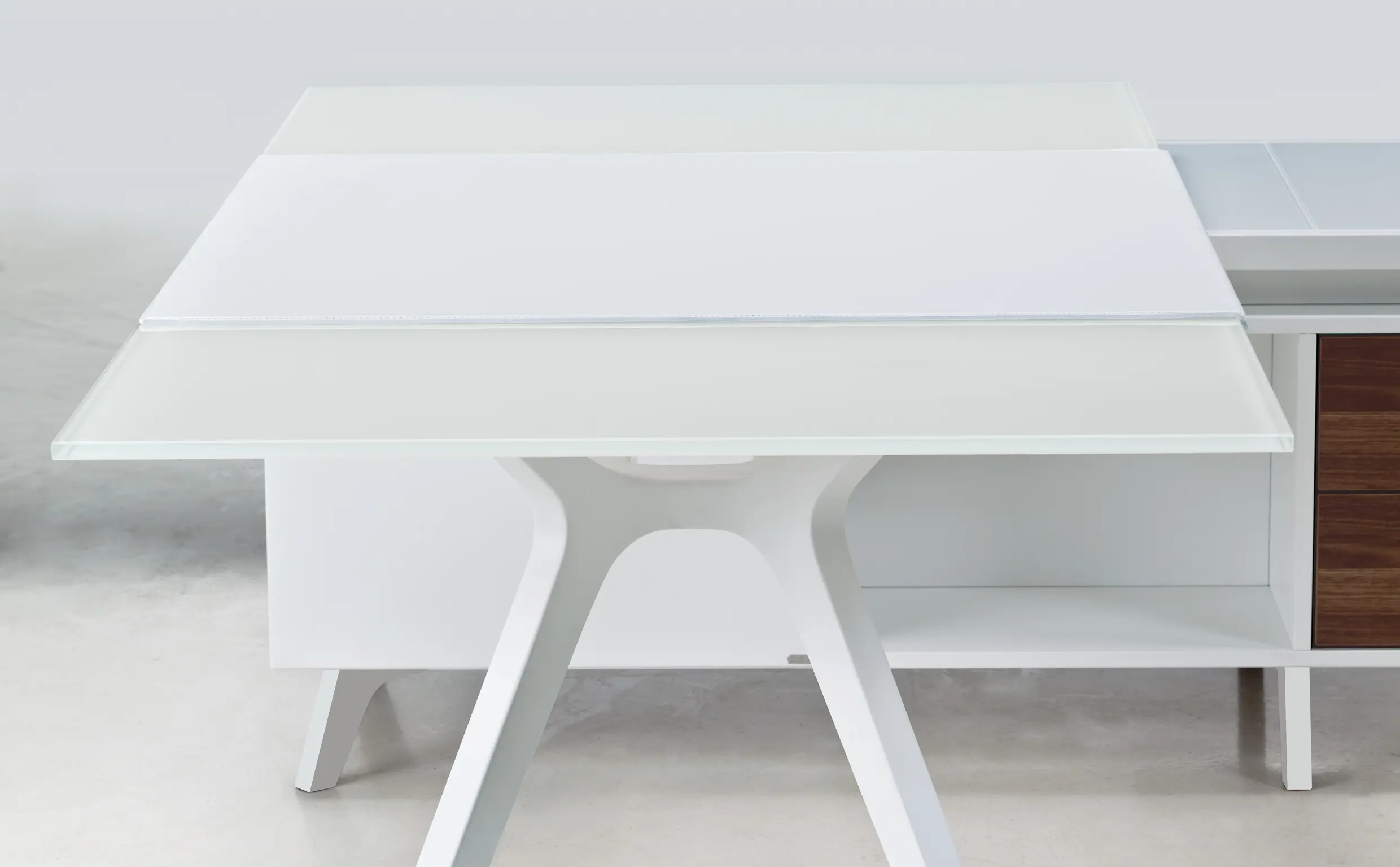 DEKKO Interiors | Αισθητική & Εργονομία στα Έπιπλα Γραφείου Η κατασκευή του γραφείου αποπνέει μια ευάερη και δυναμική αίσθηση, χάρη στην ξύλινη δομή του, η οποία είναι εμπνευσμένη από το στυλ "Mollinian". Αυτή η μοναδική κατασκευή στηρίζει είτε μια γυάλινη είτε μια ξύλινη επιφάνεια σε μια εντυπωσιακή ισορροπία αντίθετων δυνάμεων, δημιουργώντας ένα εντυπωσιακό οπτικό αποτέλεσμα. Το πολύτιμο ξύλο καρυδιάς παίζει κεντρικό ρόλο στον σχεδιασμό του γραφείου. Η επιφάνεια εργασίας, κατασκευασμένη από φυσικό καρυδιά ξύλο, είναι το αποκορύφωμα της υλικότητας και της χειροτεχνίας, με ένα συμπαγές προφίλ και στρογγυλεμένες άκρες που αναδεικνύουν τη φυσική ομορφιά του υλικού. Η γοητεία του κρυστάλλου συναντά την ισχυρή και στιβαρή αίσθηση του μαόνι kotibé στη δομή του γραφείου. Προτείνεται σε δύο εκδόσεις: λευκή και ανθρακί λάκα, προσφέροντας έτσι ευελιξία στον σχεδιασμό του εσωτερικού χώρου. Οι κρυστάλλινες επιφάνειες είναι διαθέσιμες σε τρεις εκδόσεις: εξαιρετικά διαφανές γυαλί, λευκό λακαρισμένο γυαλί, και καπνιστό γυαλί, όλα πάχους 15 mm, προσδίδοντας μία επιπλέον διάσταση πολυτέλειας.